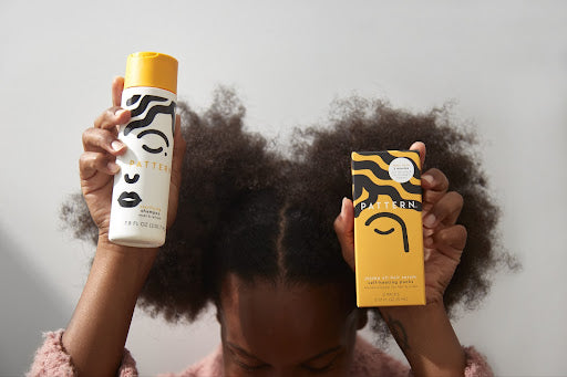 Woman with natural hail houlding in the air products for low porosity hair