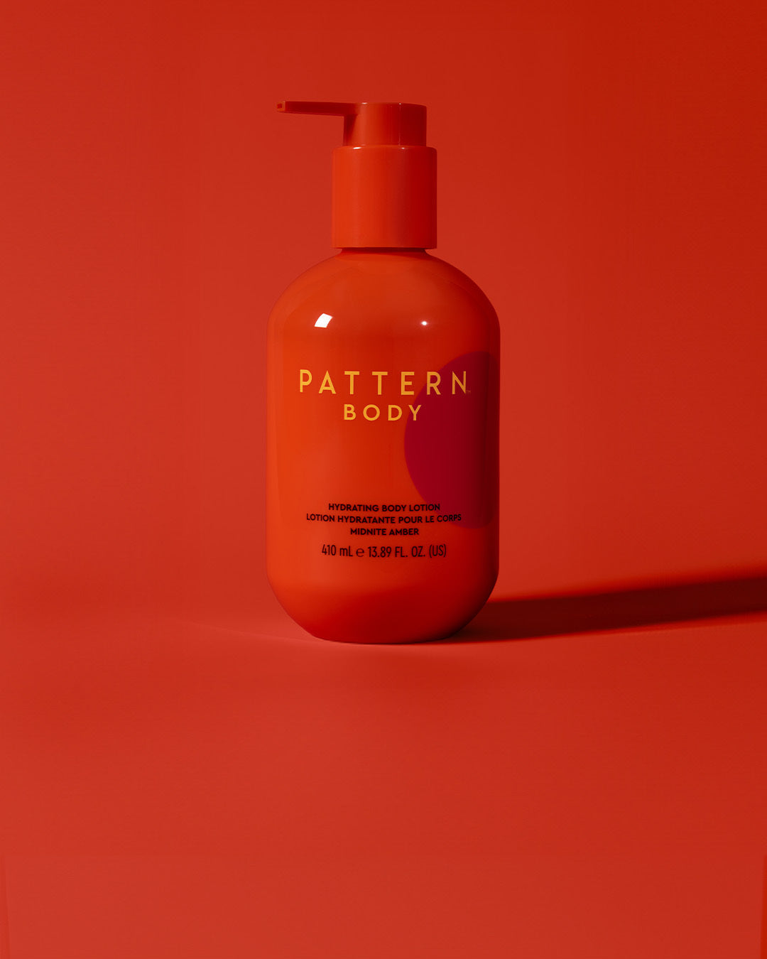 BODY-TEST GWP variant test - Orange pump bottle of PATTERN Beauty by Tracee Ellis Ross body lotion against matching orange background.