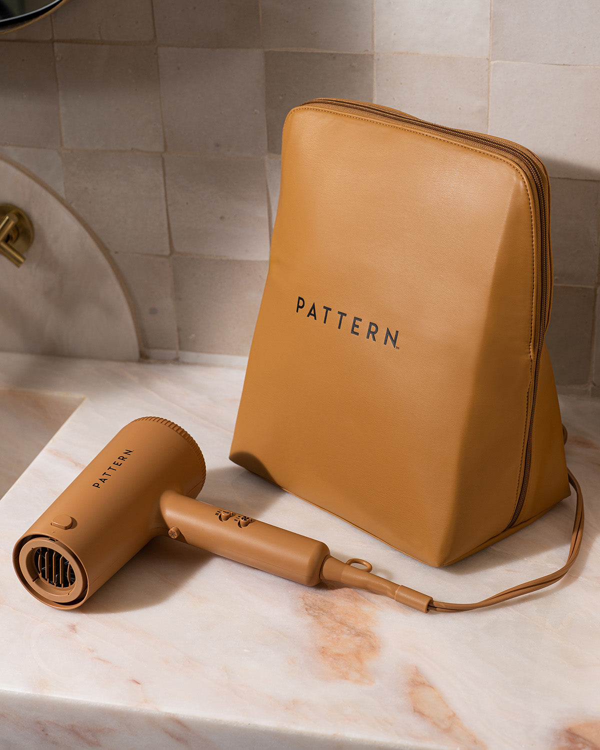 Luxe Beauty Carryall - Tan leather-look Luxe Beauty Carryall bag with black PATTERN logo beside matching compact hair dryer.