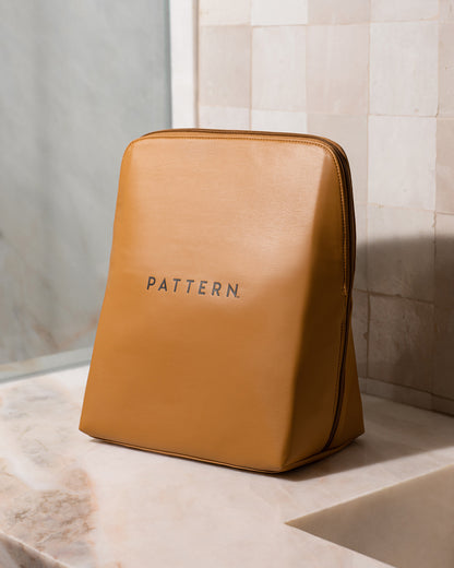 Luxe Beauty Carryall - Tan leather trapezoid beauty carryall with PATTERN Beauty by Tracee Ellis Ross logo in black centered on front.