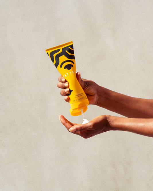 Leave-In Conditioner 9.8 FL OZ (289.8 ML)- Hand holding a bright yellow PATTERN Beauty by Tracee Ellis Ross leave-in conditioner tube over an open palm.