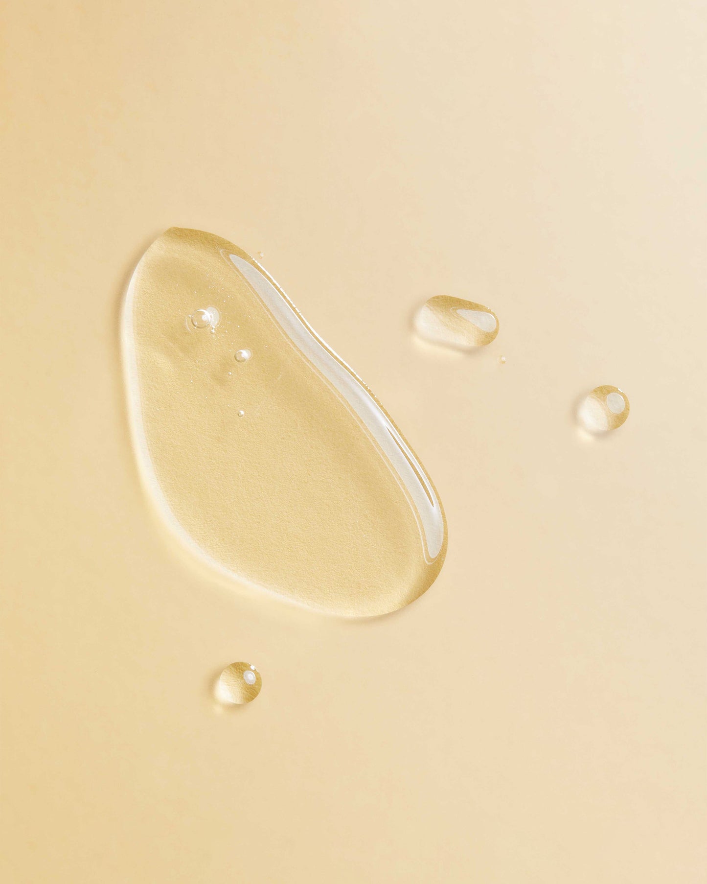 Argan Oil Blend - Clear golden argan oil droplets on a soft beige background, highlighting smooth texture and fluidity.