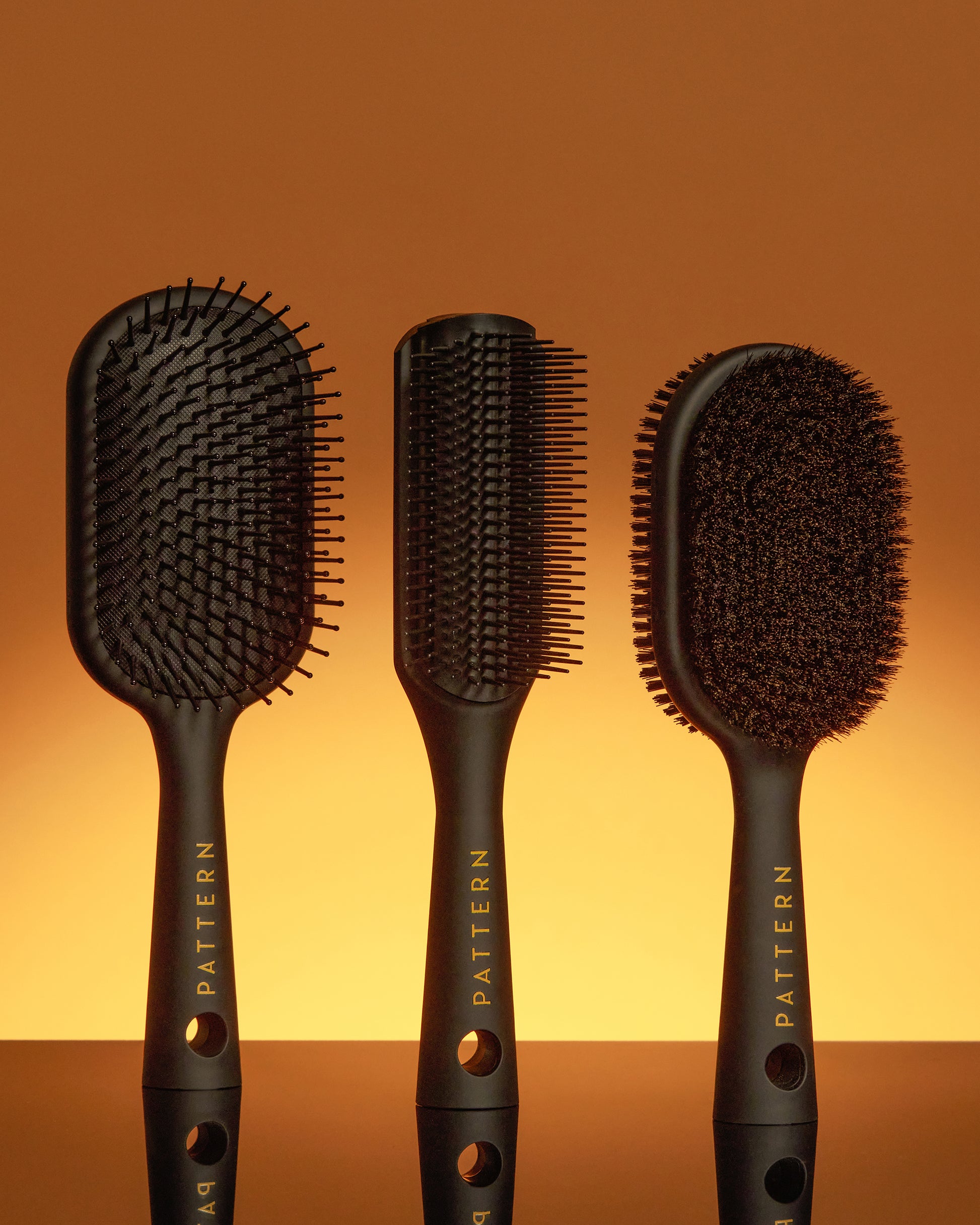 Double-Sided Bristle Brush - Set of three black hair brushes with gold PATTERN Beauty by Tracee Ellis Ross logo, featuring paddle, vent, and oval cushion .