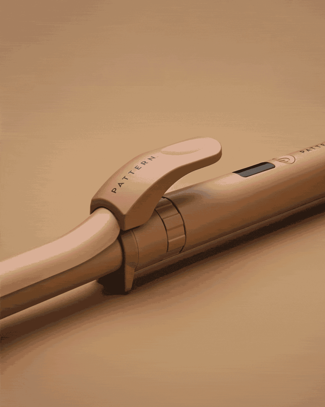 The Interchangeable Curling Iron - Sleek matte beige curling iron with ergonomic handle and PATTERN Beauty logo on clip.