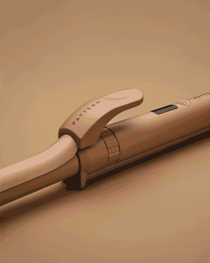 The Interchangeable Curling Iron - Sleek matte beige curling iron with ergonomic handle and PATTERN Beauty logo on clip.