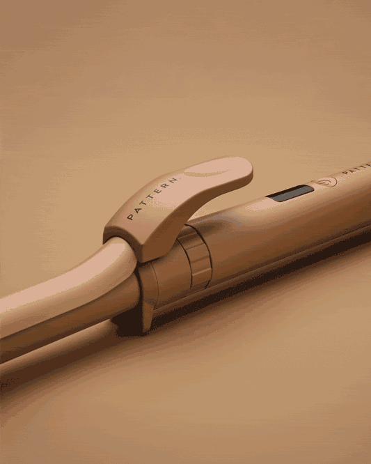 The Interchangeable Curling Iron - Sleek matte beige curling iron with ergonomic handle and PATTERN Beauty logo on clip.