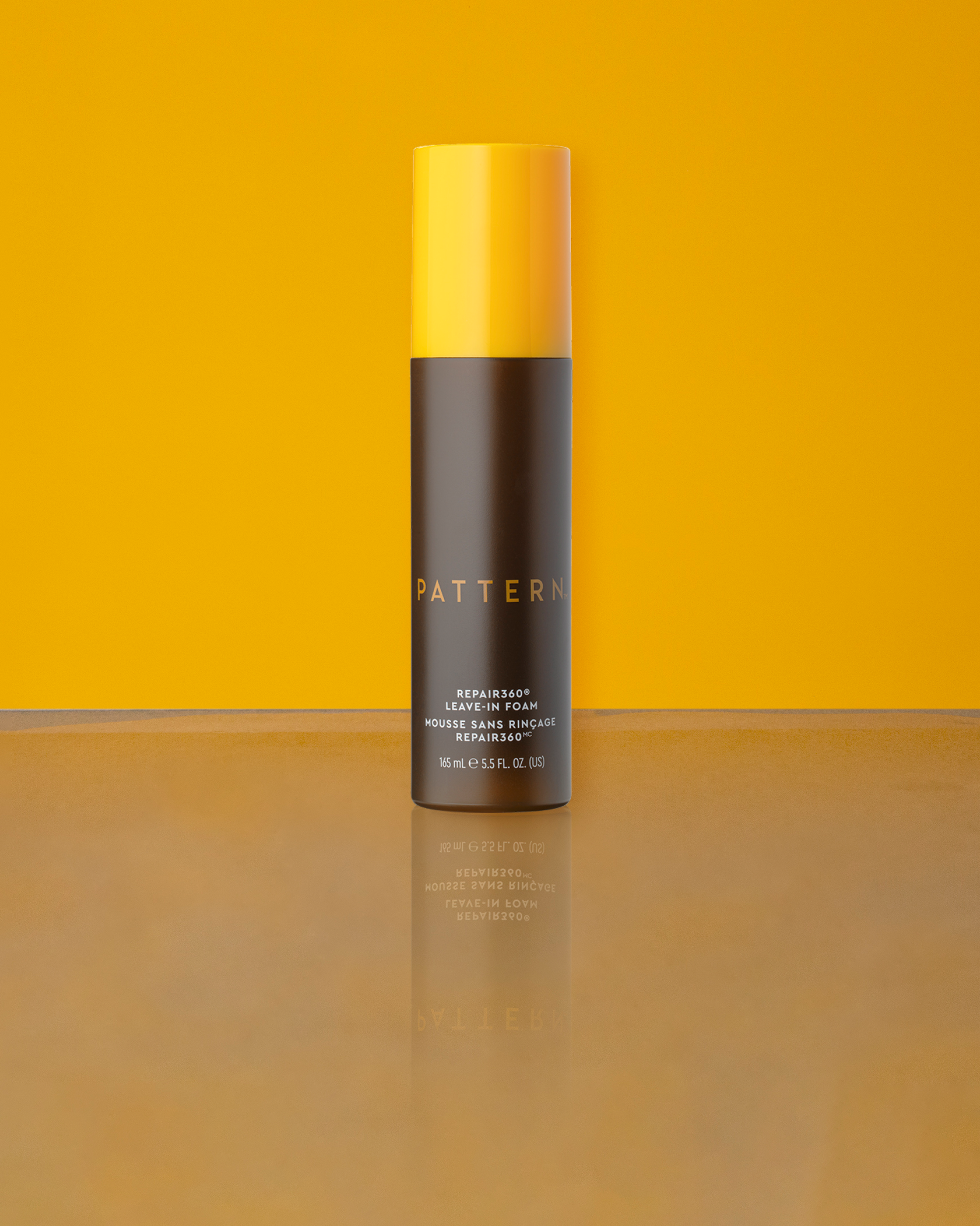Repair360®  Leave-in Foam - PATTERN Beauty Repair360® Leave-in Foam in sleek black and yellow bottle on orange background.