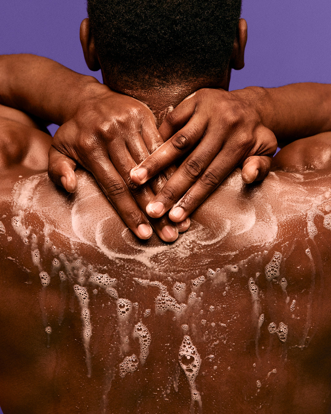 Radiant Skin Trio - Back view of a person with dark skin applying soapy lather on shoulders, highlighting PATTERN Beauty by Tracee Ellis Ross.