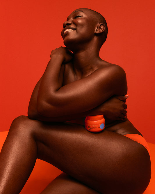 Radiant Skin Trio - Smiling woman with radiant skin holding PATTERN Beauty by Tracee Ellis Ross Radiant Skin Trio jar against orange background.