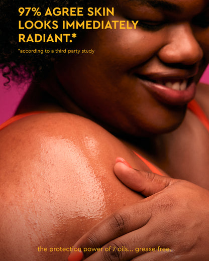 Body Full Collection Bundle - Smiling woman with glowing skin applying PATTERN Beauty by Tracee Ellis Ross body product radiant under warm light.