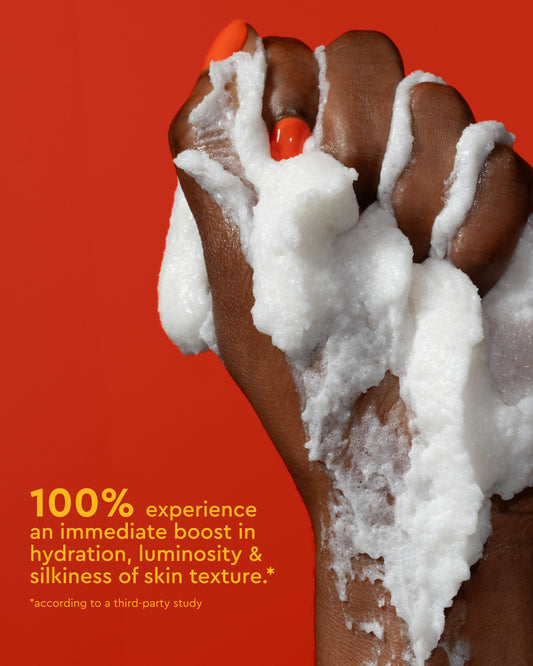 Body Full Collection Bundle - Dark-skinned hand with white foamy PATTERN Beauty by Tracee Ellis Ross body cleanser foam on bright orange background.