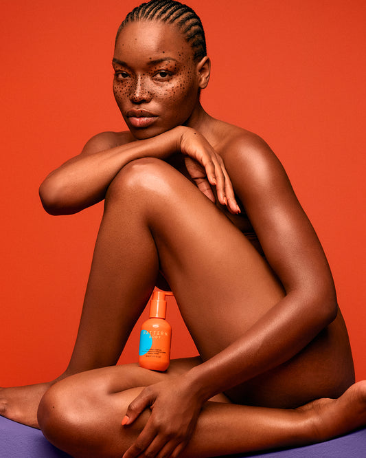 Nourishing Body Oil - Brown-skinned woman with cornrows poses nude against an orange background with PATTERN Beauty by Tracee Ellis Ross.