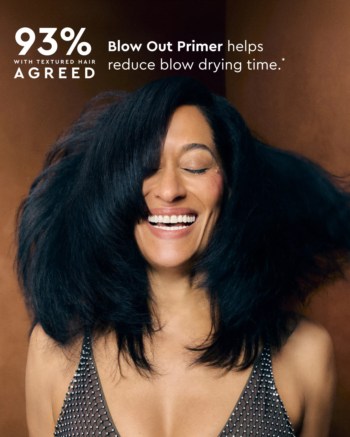 A smiling woman with voluminous dark hair is shown against a warm brown background, with promotional text reading '93% WITH TEXTURED HAIR AGREED' and 'Blow Out Primer helps reduce blow drying time.'.