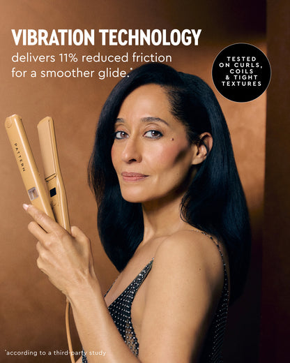 A woman with long dark hair holds a Yvonne flat iron in her hand against a warm brown studio background. Promotional text reads 'VIBRATION TECHNOLOGY delivers 11% reduced friction for a smoother glide.