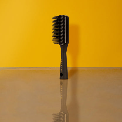 Mini Shower Brush - Black mini shower brush with short, dense bristles and PATTERN Beauty by Tracee Ellis Ross logo on handle.