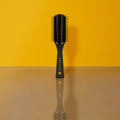 Mini Shower Brush - Black mini shower brush with short teeth and curved edges, PATTERN Beauty by Tracee Ellis Ross logo on handle.