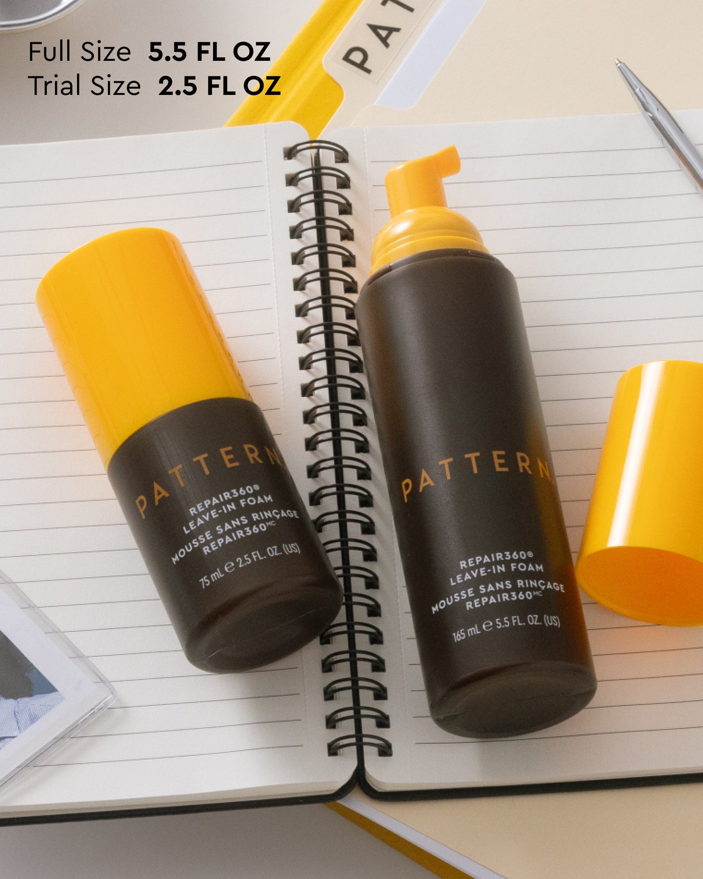 Repair360®  Leave-in Foam - PATTERN Beauty Repair360® Leave-in Foam bottles in 5.5 fl oz and 2.5 fl oz sizes with yellow caps on spiral notebook.