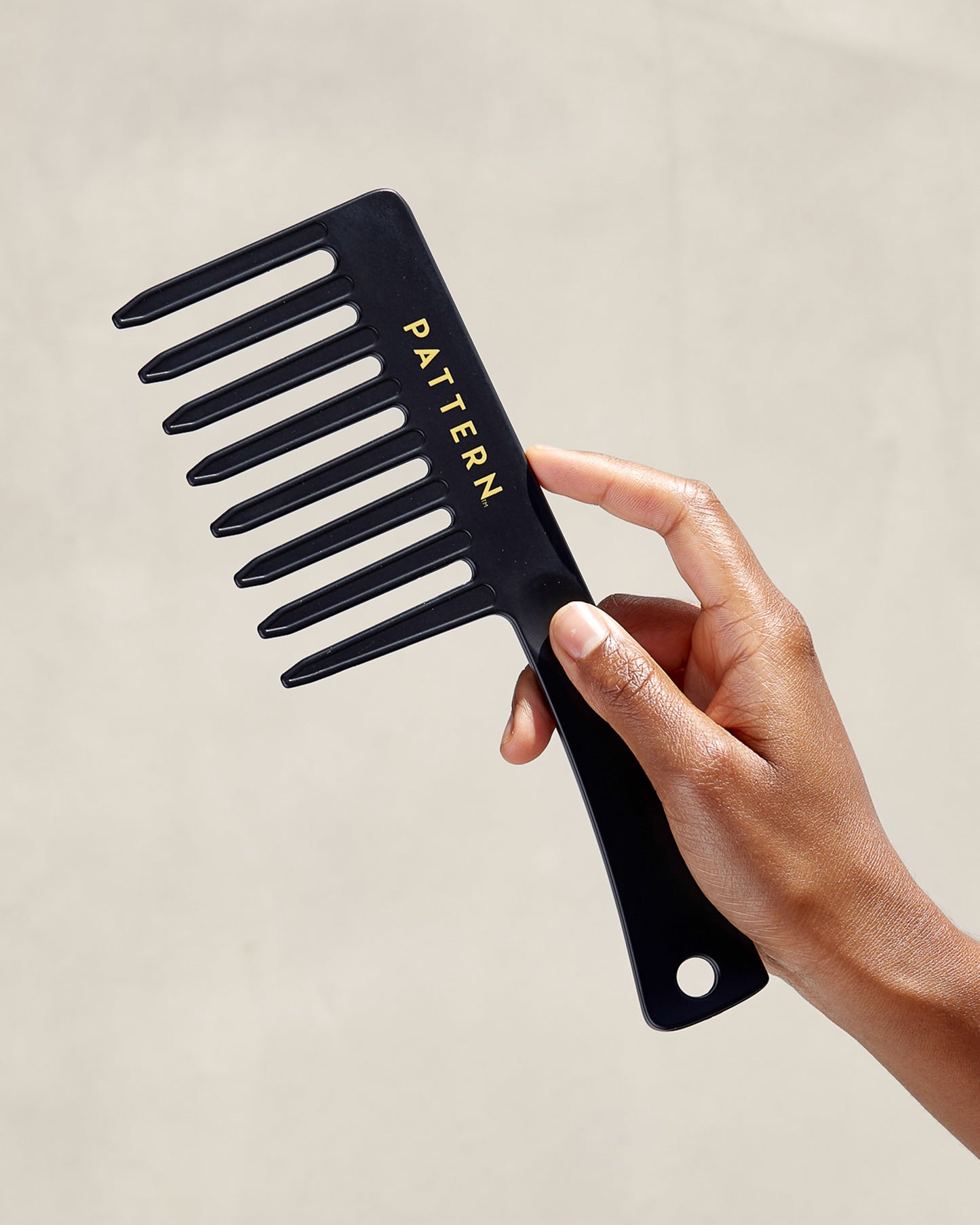 The Tight Texture Starter Bundle - Black wide-tooth comb with PATTERN Beauty by Tracee Ellis Ross logo held against neutral background.