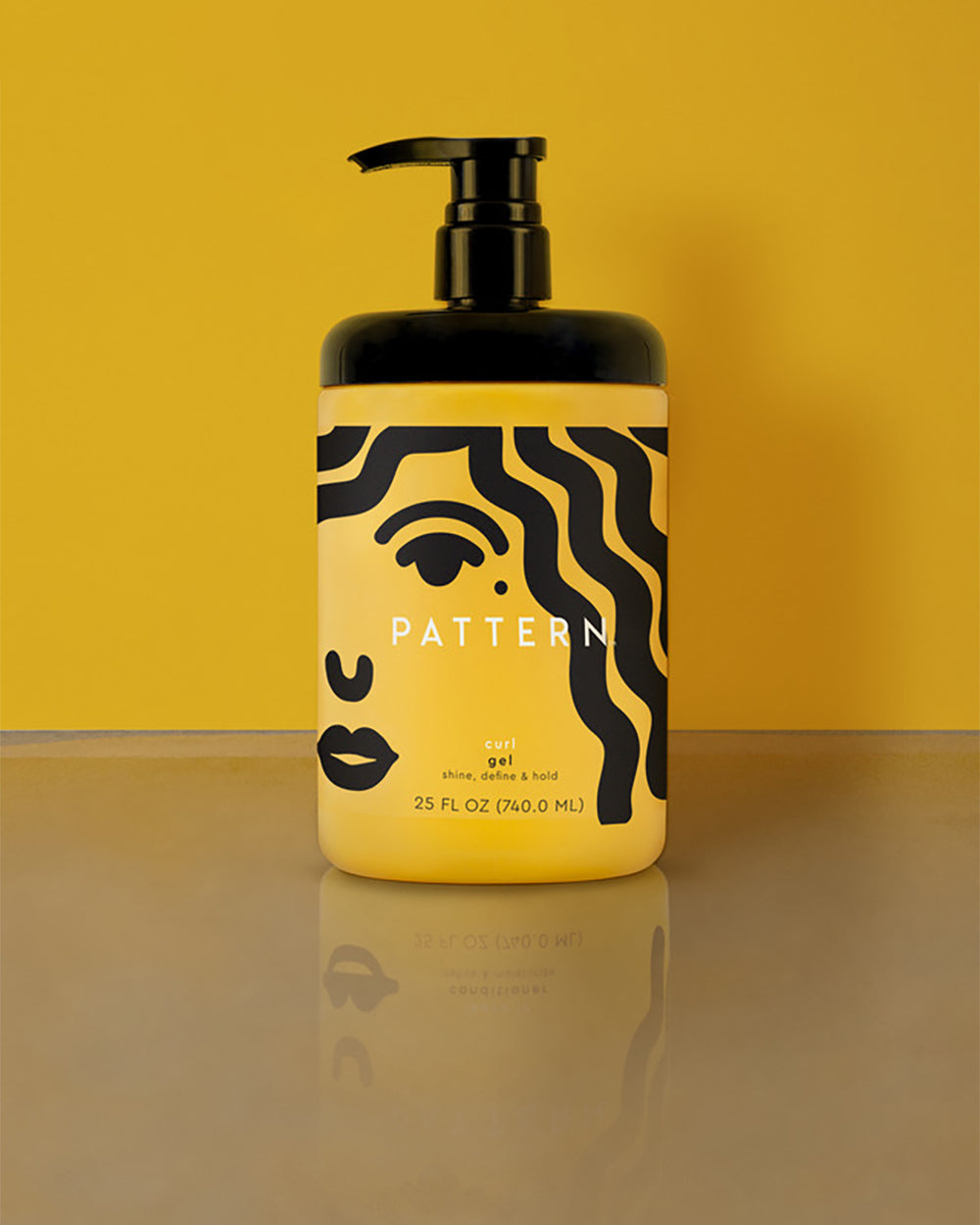 Curl Gel - Yellow plastic bottle of Pattern Beauty Curl Gel with black pump and abstract black face design on label.