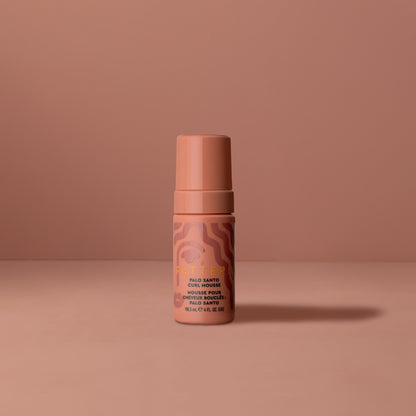 Palo Santo Curl Mousse - Small cylindrical bottle of PATTERN Beauty Palo Santo Curl Mousse in peach with abstract swirl design.