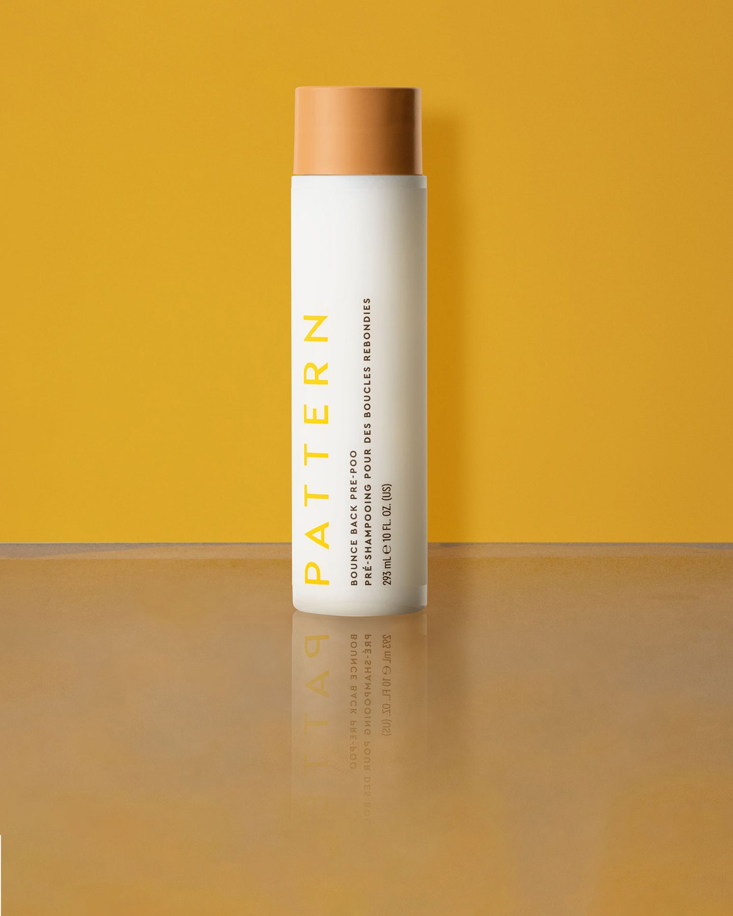 Bounce Back Pre-Poo - White cylindrical bottle with tan cap, labeled PATTERN Bounce Back Pre-Poo by Tracee Ellis Ross against a yellow background.