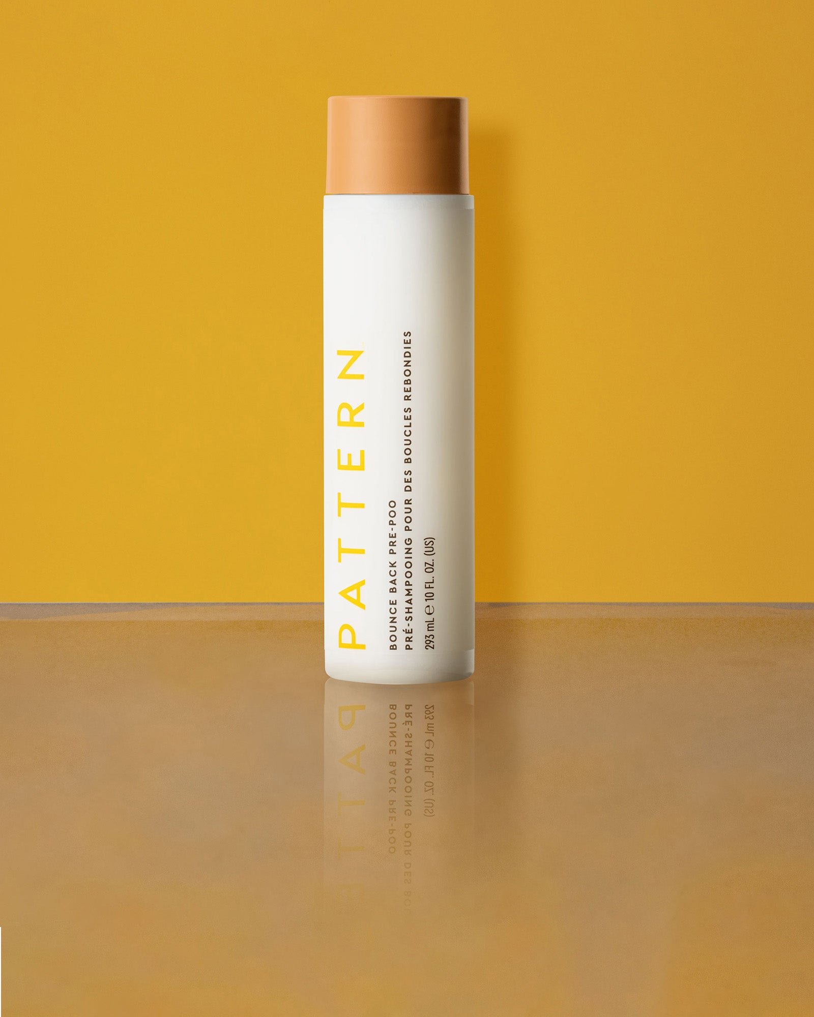 Bounce Back Pre-Poo - White cylindrical bottle with tan cap, labeled PATTERN Bounce Back Pre-Poo by Tracee Ellis Ross against a yellow background.