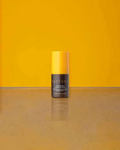 Repair360®  Leave-in Foam - PATTERN Beauty Repair360® Leave-in Foam bottle with yellow cap on reflective surface against yellow background.