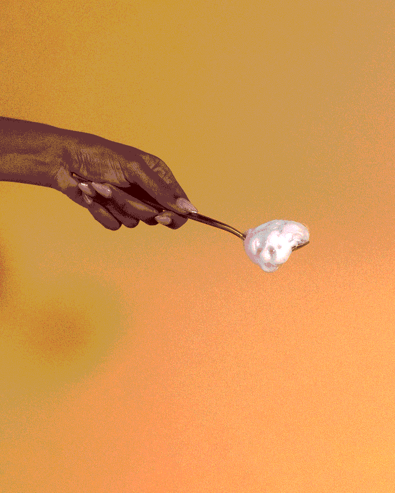 Curl Mousse - Hand holding spoon with white, fluffy curl mousse against warm orange background.